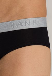 Černé bavlněné boxerky s šedým elastickým páskem s jemným vzorem loga "HANRO". Hladký povrch, minimalistický design.