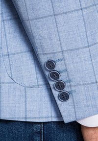 Light blue blazer sleeve with a checkered pattern, featuring four black buttons and contrasting stitching. Smooth texture.