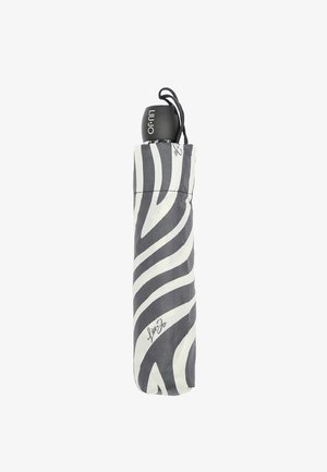 Ombrello compatto con motivo zebra bianco e nero, dotato di un manico nero e chiuso da un cordino. Presenta un dettaglio distintivo alla base.
