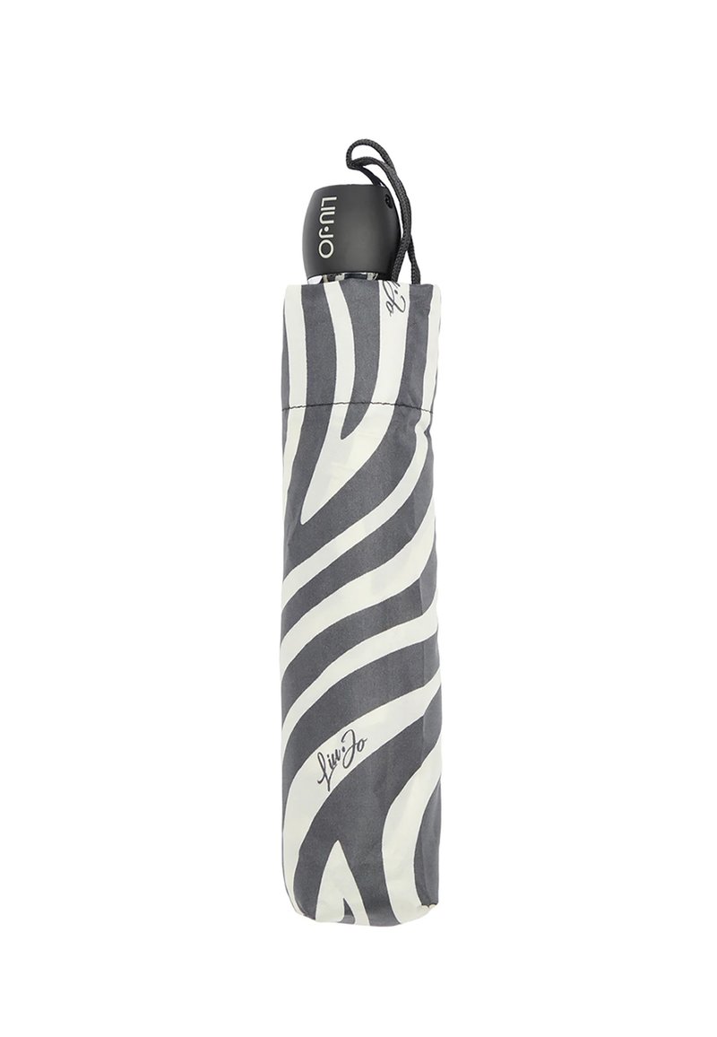 Ombrello compatto con motivo zebra bianco e nero, dotato di un manico nero e chiuso da un cordino. Presenta un dettaglio distintivo alla base.