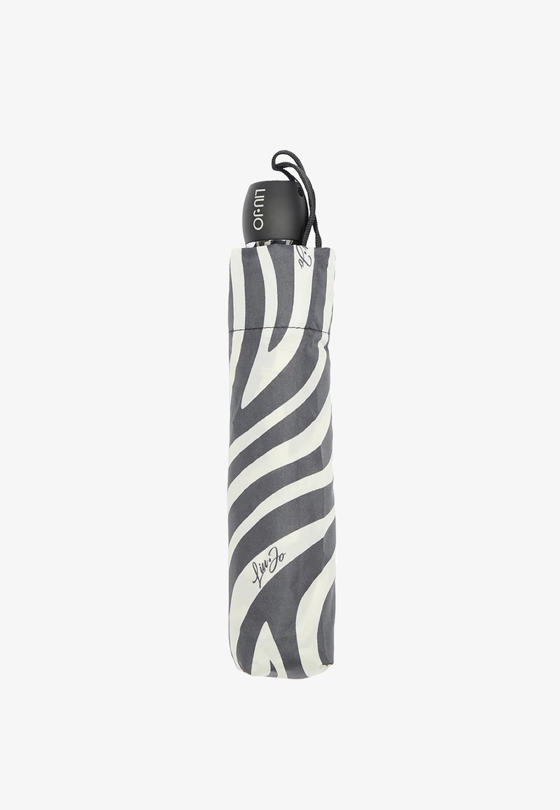 Ombrello compatto con motivo zebra bianco e nero, dotato di un manico nero e chiuso da un cordino. Presenta un dettaglio distintivo alla base.