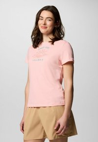 T-shirt cotone rosa chiaro a maniche corte, con una grafica del sole e il testo "SUNNY DAYS COLUMBIA" in blu.