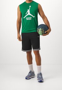 Groen mouwloos shirt met het logo van de Boston Celtics, zwarte korte broek met witte bies, grijze sneakers en een blauwe basketbal met groene accenten.