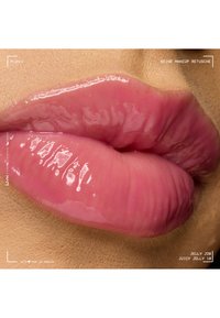 Lèvres brillantes et pulpeuses avec un gloss rose brillant sur une peau brun clair, gros plan montrant la texture et le reflet sur les lèvres.