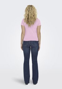 Rosa ribbet kortermet topp kombinert med mørkeblå flarejeans. Jeansene har baklommer og litt falming ved kanten.