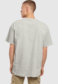 Šedé bavlněné tričko s krátkými rukávy, kulatým výstřihem a volným střihem, které má hladkou texturu a žádné výrazné vzory nebo akcenty.