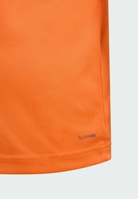 Oranžová sportovní tričko vyrobené z hladkého, lehkého materiálu, s prodyšným designem. Výrazné označení "CLIMACOOL" poblíž lemu.