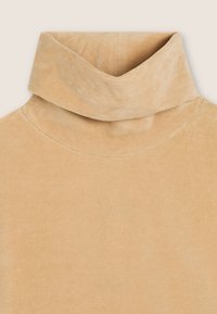 Top beige a collo alto realizzato in un morbido tessuto testurizzato. Il colletto è piegato in modo prominente, offrendo una vestibilità aderente. Design semplice e senza cuciture.