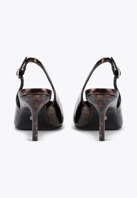 Scarpe con tacco alto in pelle verniciata marrone con design slingback, punta affusolata e accenti più scuri a contrasto. Presentano una fascia con fibbia nel tallone.