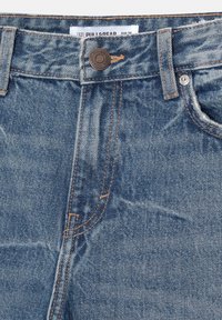 Jean en denim bleu taille avant avec bouton en métal, passants de ceinture, rivet de poche avant et étiquette Pull&Bear taille 34 visible.