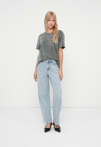 Γκρι ριγέ πλεκτό μπλουζάκι με κοντά μανίκια συνδυασμένο με ψηλόμεσα ανοιχτά μπλε τζιν. Μαύρα στιλέτο ολοκληρώνουν την εμφάνιση.