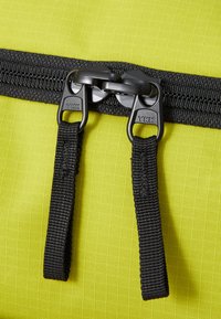 Geel stoffen tas met een dubbele zwarte rits met YKK-merk, gestructureerde ritsrepen en een gladde, duurzame oppervlakte.