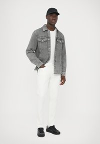 Γκρι τζιν μπουφάν με τσέπες στο στήθος, λευκό μπλουζάκι, λευκό παντελόνι και μαύρα αθλητικά παπούτσια. Μαύρο καπέλο ολοκληρώνει την εμφάνιση. Απλός, καθαρός σχεδιασμός.