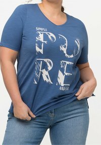 Blå kortärmad t-shirt med V-ringning, med vit text "SIMPLE PURE AND EASY" i ett borstat typsnitt. Mjuk textur, avslappnad passform.