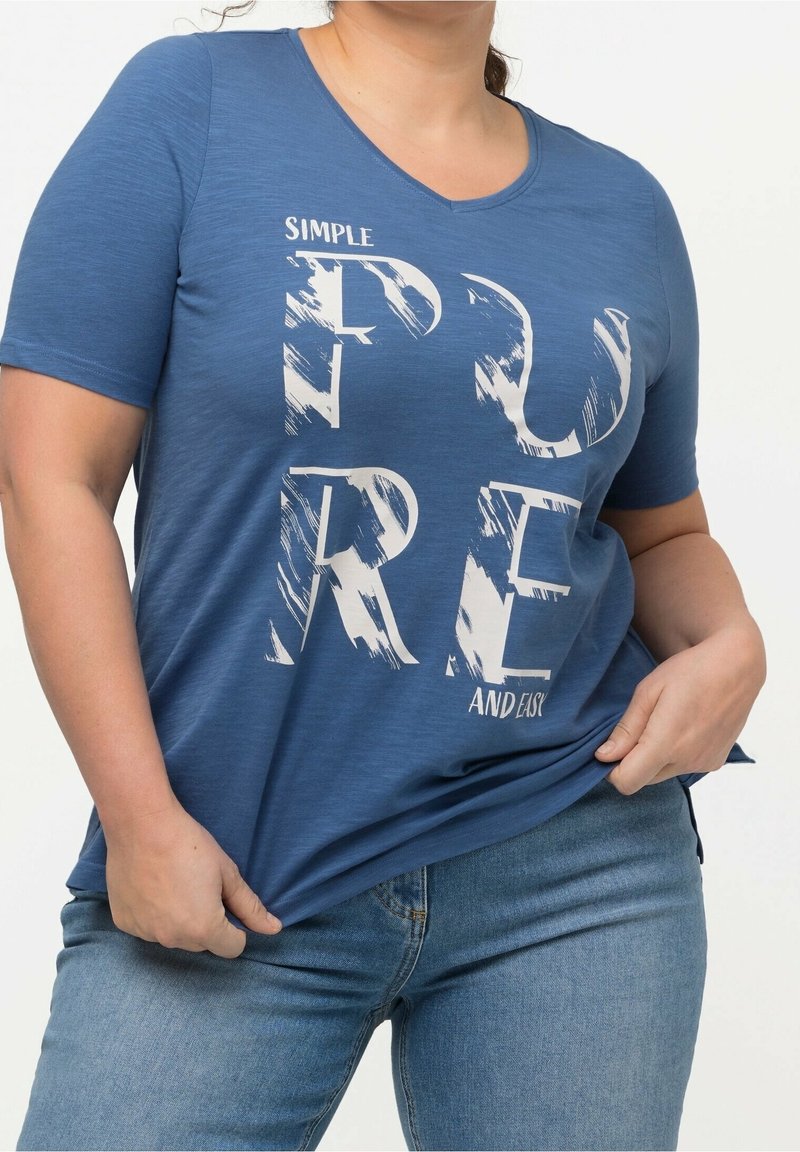 Blå kortärmad t-shirt med V-ringning, med vit text "SIMPLE PURE AND EASY" i ett borstat typsnitt. Mjuk textur, avslappnad passform.