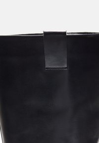 Borsa a tracolla nera in pelle con una texture liscia, lati piatti e una maniglia superiore cucita. Design minimalista senza hardware o accenti visibili.