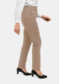 Beige op maat gemaakte broeken met een gladde textuur, een elastische tailleband en zijzakken, gecombineerd met zwarte hoge hakken.