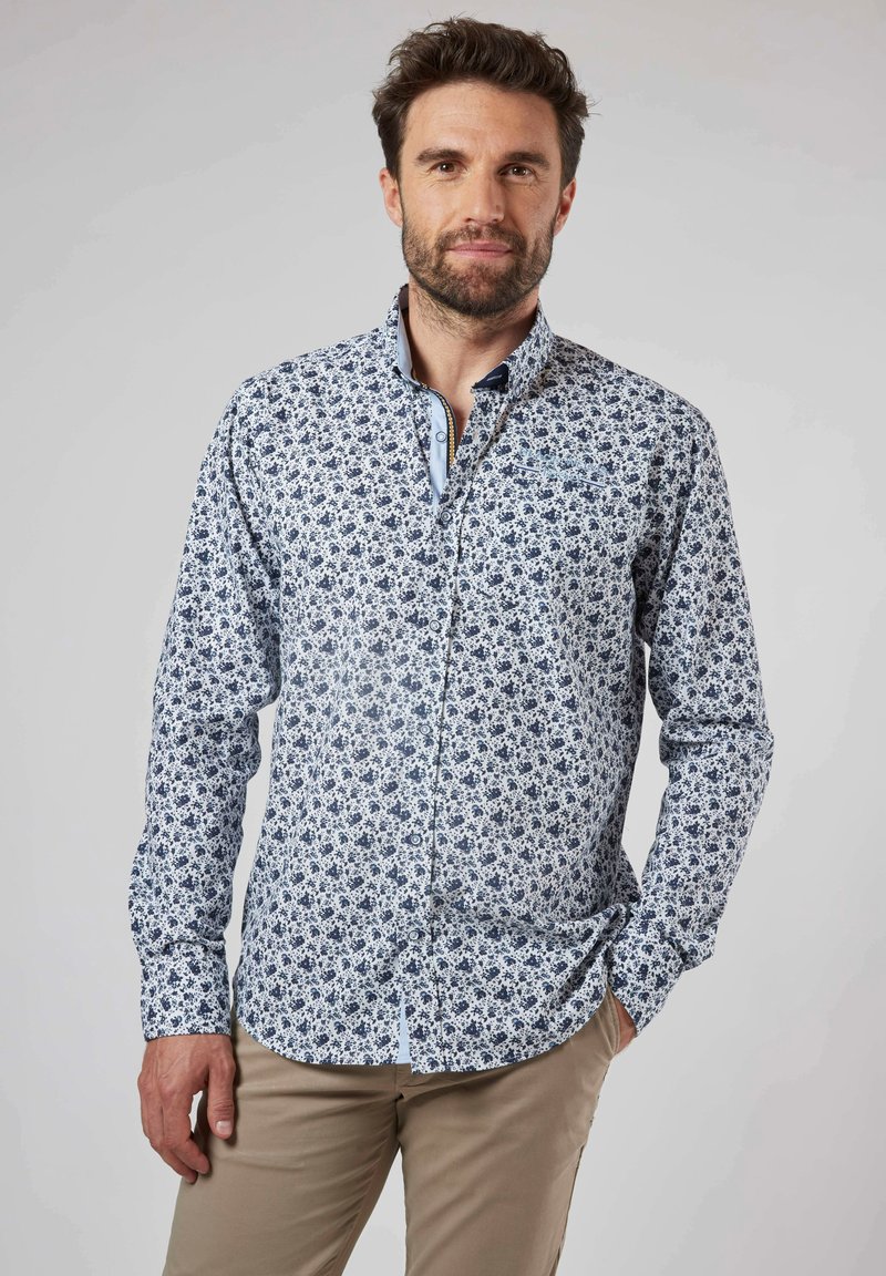 Chemise à manches longues pour homme en blanc avec un motif floral bleu, col contrasté, boutonnière avant et poignets ; fabriquée en tissu de coton léger.