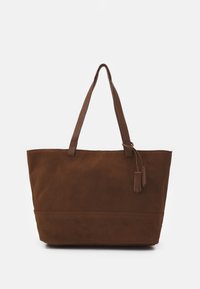 Stor brun mockaväska med två långa handtag och två små hängande läderlappar på en helt vit bakgrund.