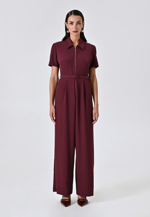 Burgunderfarbener Jumpsuit aus leichtem Material, mit kurzen Ärmeln, einem Reißverschluss auf der Vorderseite, einem Gürtel in der Taille und weitem Bein.