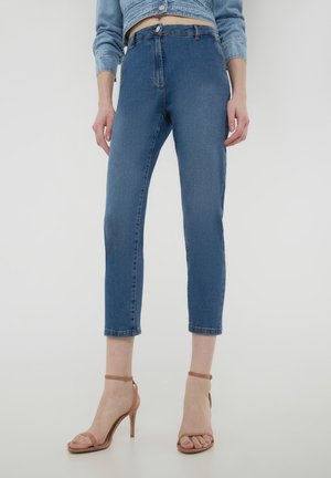 Jeans skinny in denim blu con vita alta, lunghezza cropped e classico stile a cinque tasche. Abbinati a sandali con tacco alto color nude.