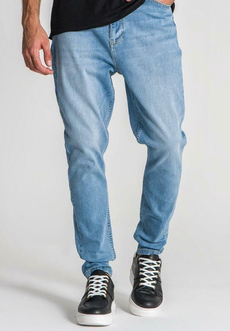 Ljusblå denimjeans med en avslappnad passform, med en klassisk femfickedesign och avslutade med svarta och vita sneakers.