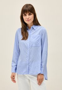 Light blue button-up shirt with white vertical stripes, single chest pocket, long sleeves, and relaxed fit, made from a smooth fabric.