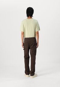 Light green short-sleeve shirt and brown cargo pants with elastic waistband, featuring side pockets, worn with beige shoes.