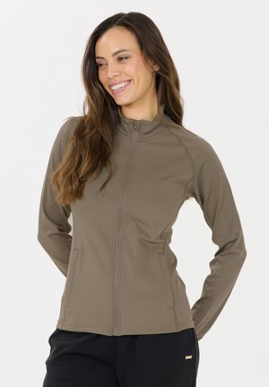 Braune Zip-Jacke aus glattem, dehnbarem Material mit hohem Kragen und Seitentaschen. Taillierte Passform mit subtilen Nahtdetails.