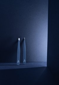 Pinzas de metal con un acabado mate azul oscuro elegante, con dos puntas anguladas en un diseño minimalista. Acentuadas con un logo sutil.