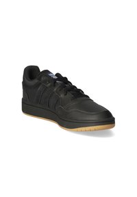 Baskets de sport noires avec un dessus en cuir, quatre rayures noires et une semelle en caoutchouc texturé. Comprend des lacets ronds et un col rembourré pour le confort.