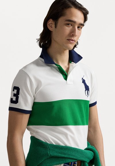Polo krekls ar zaļām, baltām un tumši zilām svītrām, izgatavots no kokvilnas materiāla, ar izšūtu logo un numuru 3 uz piedurknes. Pulovers sasiets ap jostasvietu.