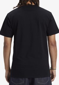 Svart bomullströja med korta ärmar, rundad hals och en slät yta. Bakvy visar inga mönster eller logotyper. Ren och enkel design.