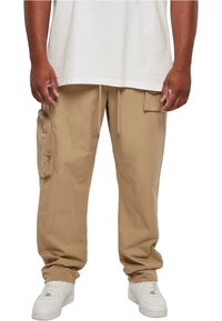 Beige cargo pants with side pockets and a drawstring waist, made of lightweight fabric, paired with white sneakers and a loose-fitting white shirt.