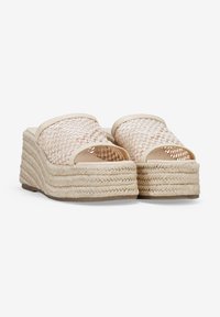 Sandalias de plataforma de paja tejida con punta abierta, que presentan un color beige, una parte superior de tela texturizada y una suela de yute trenzado en capas.