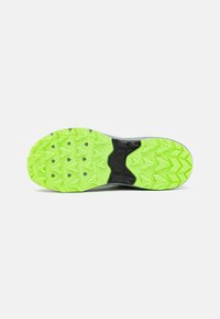 Suela de zapato con una combinación de colores negro y verde vibrante, con patrones de textura en zigzag para mayor tracción. El diseño es atlético y duradero.