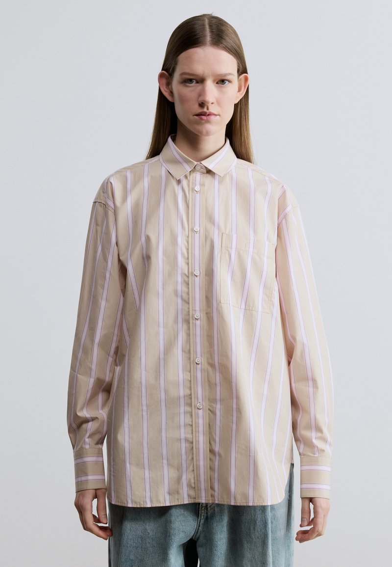 Hellrosa gestreiftes Hemd mit langen Ärmeln, einer einzelnen Tasche und spitzem Kragen. Hergestellt aus einem glatten Stoff mit legerer Passform.