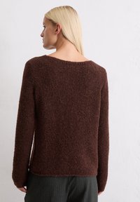 Pruun, tekstuuriga sviiter pikkade varrukatega ja laia kaelusega, millel on pehme ja karvane kangas. Seljaosa kuvab lihtsa ja puhta disaini.