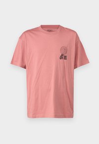 Camiseta de algodón rosa con cuello redondo, mangas cortas y un estampado gráfico en el lado izquierdo del pecho que presenta texto y un elemento de diseño.