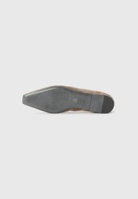 Semelle de chaussure en daim, marron avec une texture antidérapante, nez légèrement pointu et un accent de talon noir solide. Détail de marque imprimé présent.