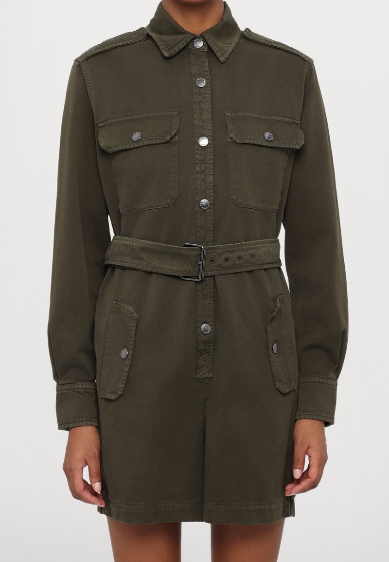 Robe-chemise ceinturée vert olive à manches longues, quatre poches à rabat avec boutons et boutons-pression argentés devant.