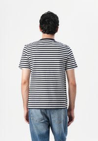 Striped T-shirt in navy and white cotton. Short sleeves, crew neck, with a relaxed fit. Back view shows horizontal stripes and minimal detailing.