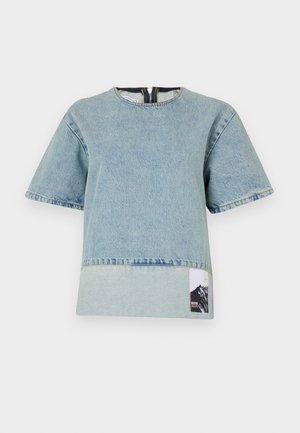 Light blue denim t-shirt with short sleeves, rounded neckline, contrasting bottom panel, and a mountain graphic label on the left side.