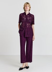 Set due pezzi in pizzo di colore viola scuro, composto da una camicia a maniche corte con bottoni e pantaloni a gamba larga con delicate sfide floreali. Scarpe nere completano il look.