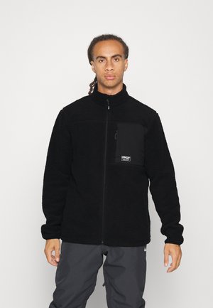 Black fleece jacket with a high collar, front zipper, and a chest pocket in a contrasting fabric. Uniform texture and snug fit.