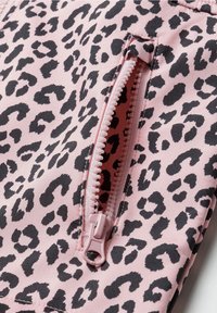 Tela rosa con un estampado de leopardo negro; cuenta con un bolsillo frontal con cremallera rosa y detalles de dientes de nailon blancos.