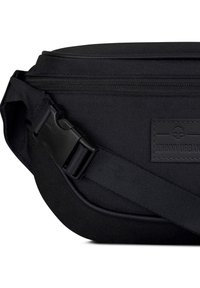Černá taška přes rameno vyrobená z odolné tkaniny, s texturovaným povrchem, nastavitelným popruhem a pevným plastovým sponou. Viditelná nášivka s logem.