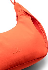 Narancssárga szövet válltáska ívelt formával, cipzáras záródással és dombornyomott logó részletekkel. Simább textúra, minimalista dizájn.