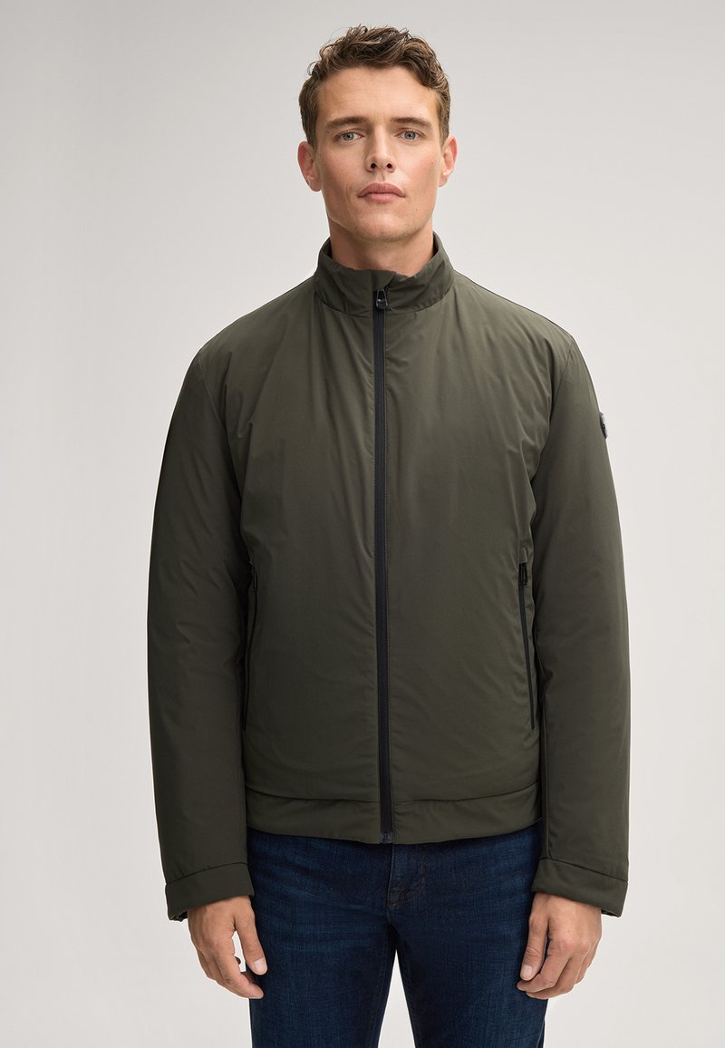 Giacca leggera verde da uomo con colletto rialzato, zip frontale completa, tasche laterali e una texture di tessuto liscia e resistente all'acqua.