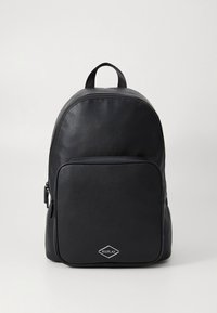 Sac à dos en cuir noir de forme arrondie, avec une poche avant zippée et un logo en forme de losange. Texture lisse et bretelles doubles réglables.
